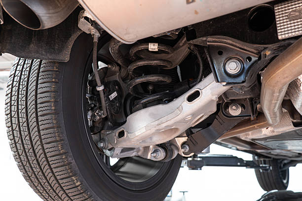 istock Car rear axel assembly with control arm, coil spring and shock absorber. Wide angle, looking up shot of a lifted car in a repair shot, no people 2231272993