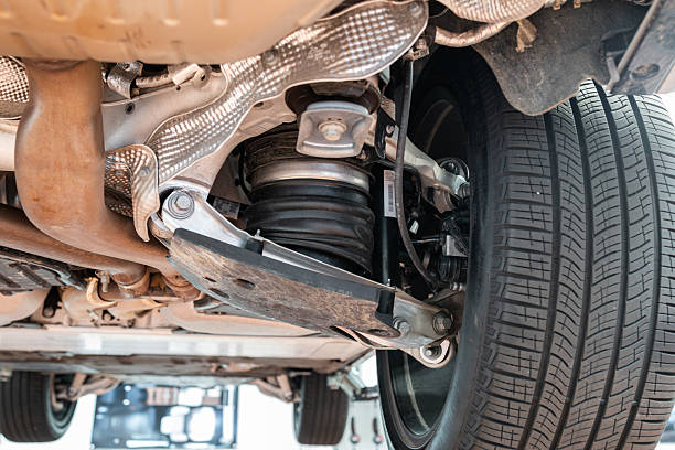 istock Car rear axel assembly with control arm, air suspension shock absorber with rubber boot. Wide angle, looking up shot of a lifted car in a repair shot, no people 2231273020
