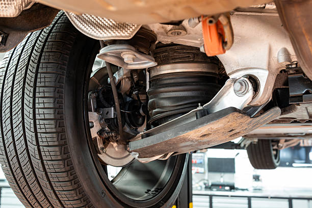 istock Car rear axel assembly with control arm, air suspension shock absorber with rubber boot. Wide angle, looking up shot of a lifted car in a repair shot, no people 2231273022