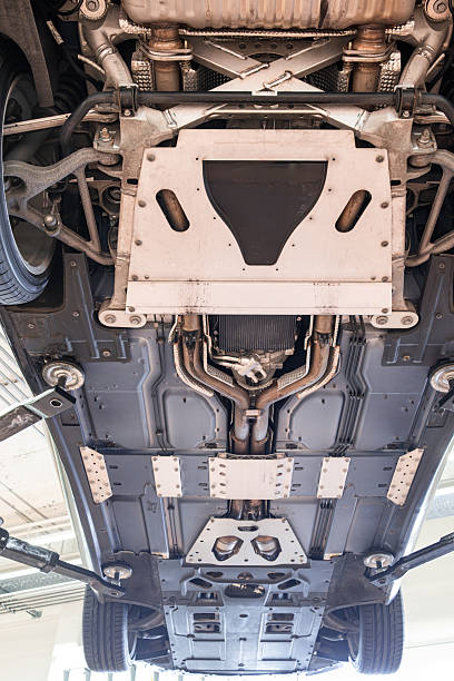 istock Car undercarriage with exhaust system, wheels and axel components. Wide angle, looking up view, car suspended on a lift, inside repair shop, no people 2231273087