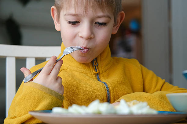 istock 6 years old boy eats pasta with cheese from blue plate. Child is eating spaghetti. Lunch time. Good appetite. Tasty children food. Close-up portrait. Carbs dinner. Fast food. Kid eating with fork. 2231278863