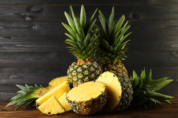 istock Whole and cut ripe pineapples on wooden table 2231281918
