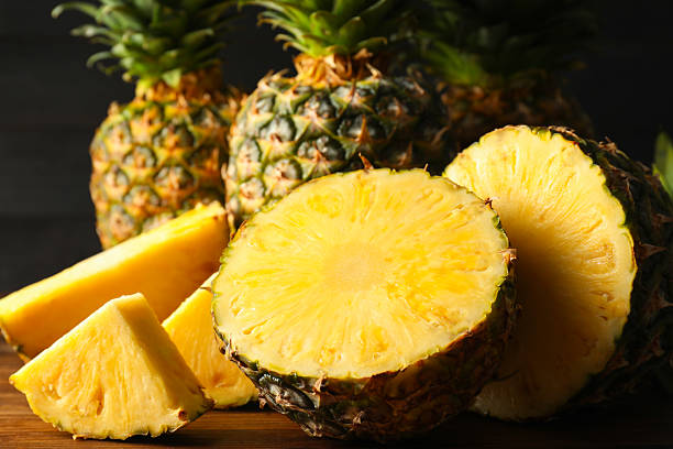 istock Whole and cut ripe pineapples on wooden table, closeup 2231281934