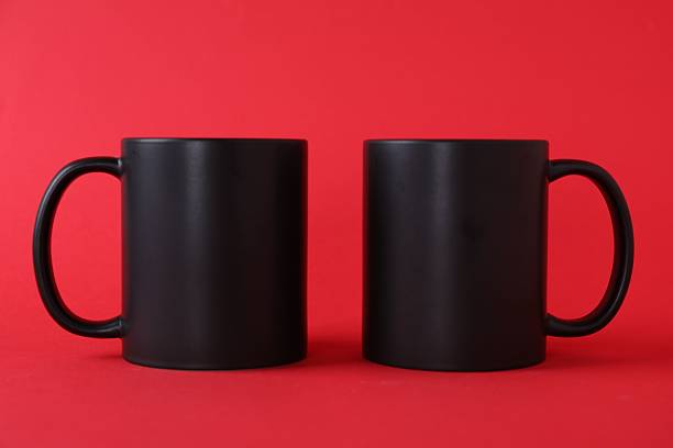 istock Two blank black mugs on red background. Mockup for design 2231282042