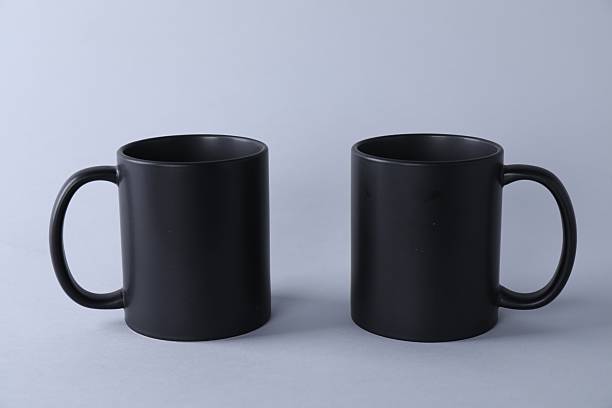 istock Two blank black mugs on light background. Mockup for design 2231282043