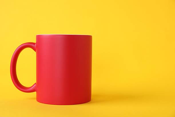 One red ceramic mug on yellow background