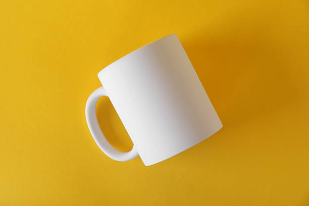 istock One blank white mug on yellow background, top view. Mockup for design 2231282462
