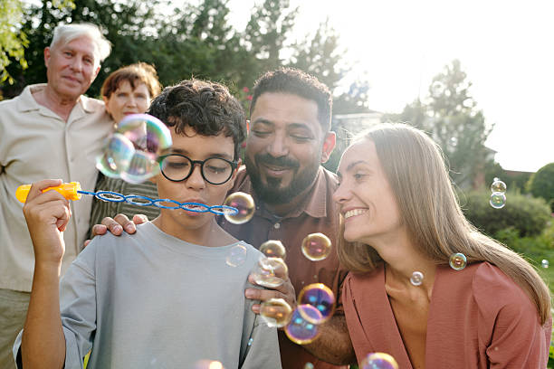 istock Multiethnic Family Watching Child Blowing Bubbles Outdoors in Sunlight 2231282910