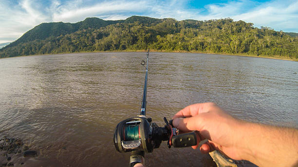 istock Fisherman casting line into amazon river with lush rainforest in background 2231283099