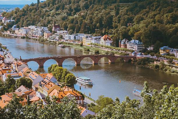 The photo captures a wide view of the famous Heidelberg Old Town on the Neckar River. In the center of the picture, the historic Old Bridge with its distinctive arches elegantly spans the water.