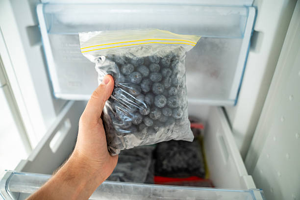 istock Man hands hold zip bag with blueberries, putting into freezer. Storing summer berry for future use 2231285754