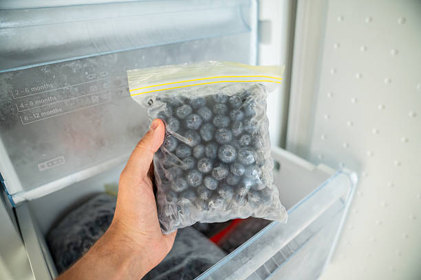 istock Man hands hold zip bag with blueberries, putting into freezer. Storing summer berry for future use 2231287973