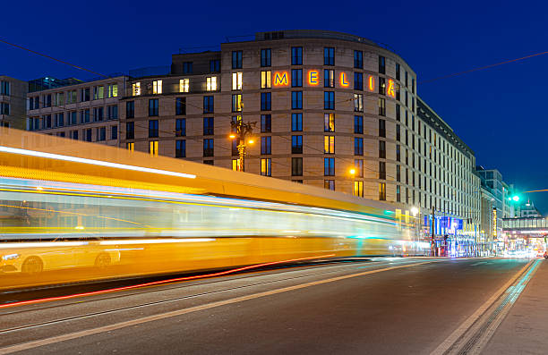 Germany, Berlin, Central Berlin, Friedrichstrasse,  August 19, 2025 - Blurred motion of Berlin tram on the Friedrichstrasse against building at night