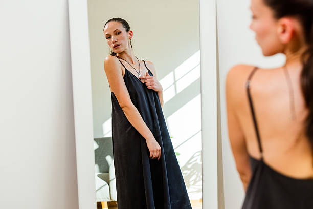 young beautiful girl in the Studio and its reflection in the mirror. Black dress. Light grey background