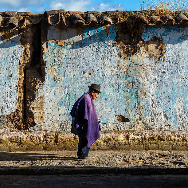 Senior Ecuadorian man walking in front of colourful traditional facade with traditional clothing in Quito, Ecuador.
