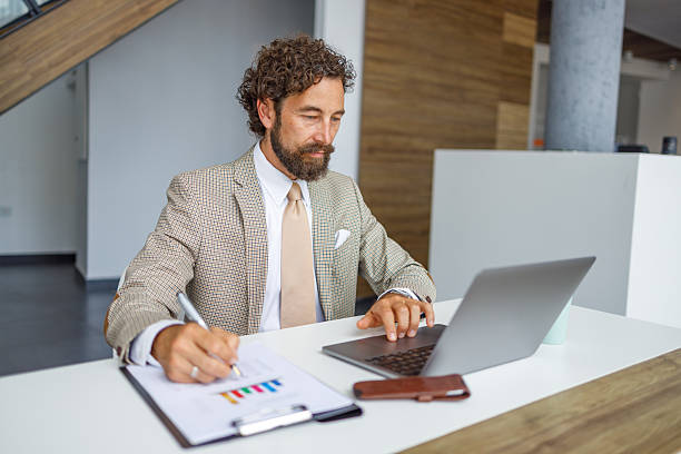 istock Businessman analyzing financial data and working on a laptop in a modern office 2231296473