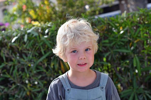 A curly little boy is looking at the camera