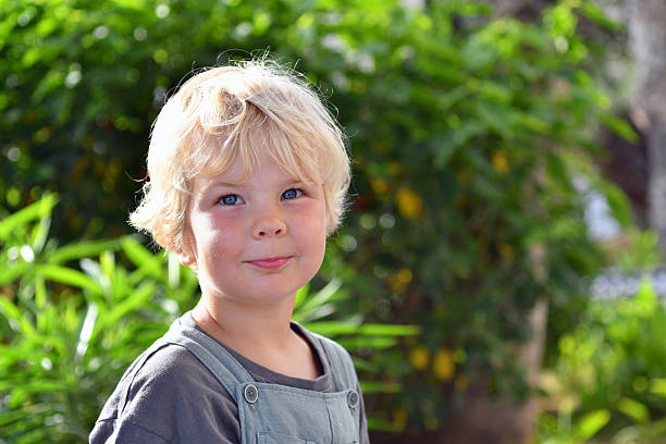 Smiling Blond Boy Portrait Outdoors with Green Nature Background