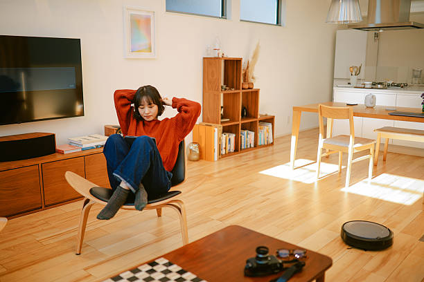 istock Woman relaxing and reading while the automatic vacuum cleaner is on 2231298105