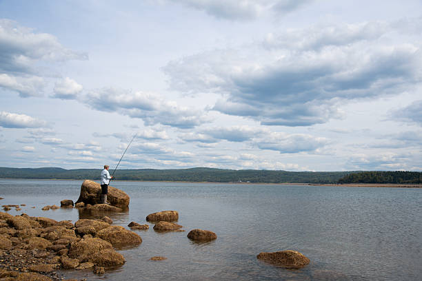 A sport fisherman fishing for striped bass on a beach in the Annapolis Valley of Nova Scotia, Canada.