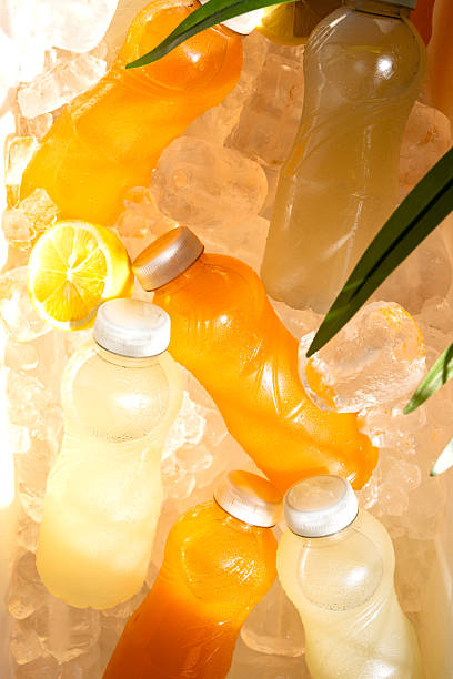 istock Refreshing fruit juice bottles cooling on ice with lemon slice and palm leaf, perfect for a hot summer day 2231308263