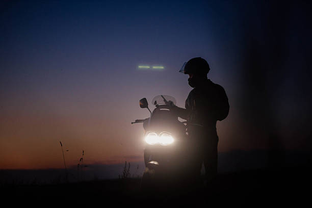 Motorcyclist with motorcycle in helmet at night with headlights on in nature May 27 2023