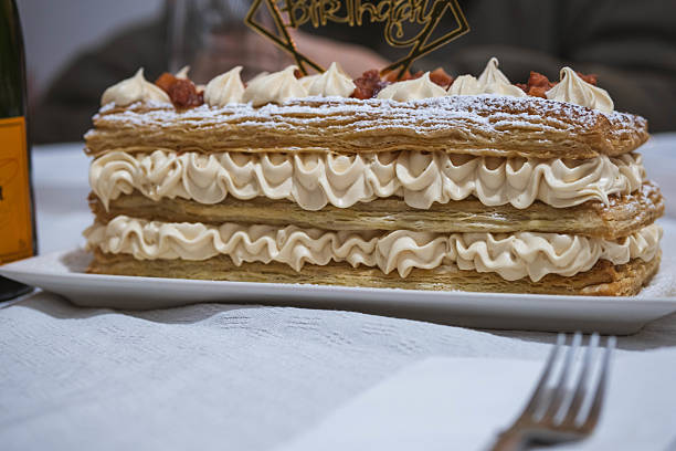 A birthday cake with a gold star on top. The cake is decorated with powdered sugar and has a frosting on top