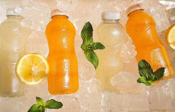 istock Chilled plastic juice bottles resting on ice, accompanied by mint leaves and lemon garnish 2231314068