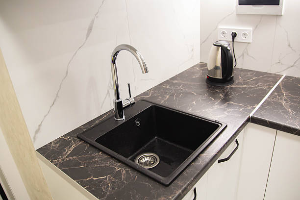 istock Black modern sink with water tap built into granite worktop in kitchen, industry 2231315303