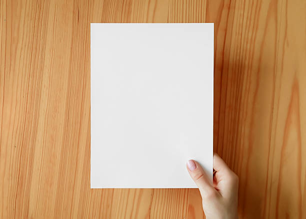 istock Hand holding blank paper on a wooden surface 2231315504