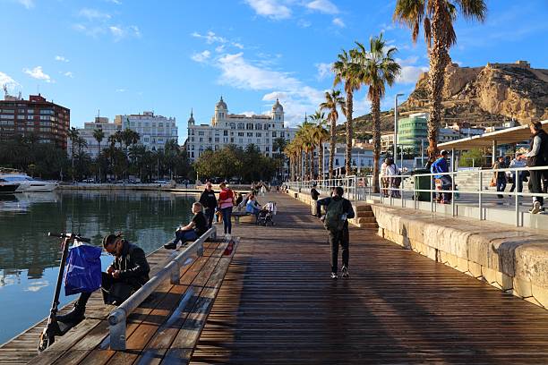 People visit the harbor front walkway Paseo de los Martires de la Libertad in downtown Alicante, Spain.