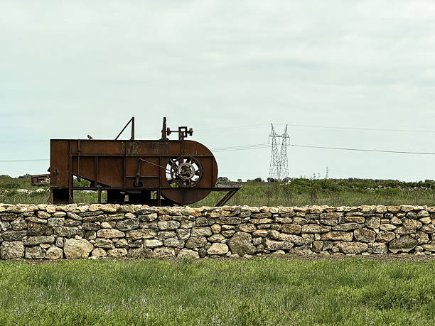 Antique winnowing machine displayed outdoors on stone wall in Castilla y Leon