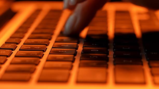 Close Up of Hands Typing on Keyboard in Dim Lighting