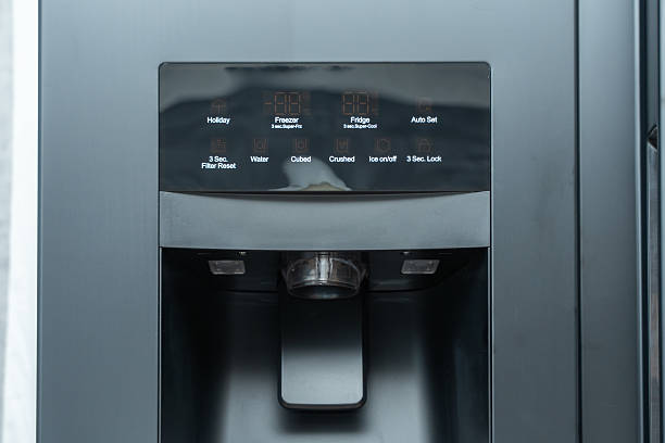 Close-up of a refrigerator's control panel with display and water dispenser.