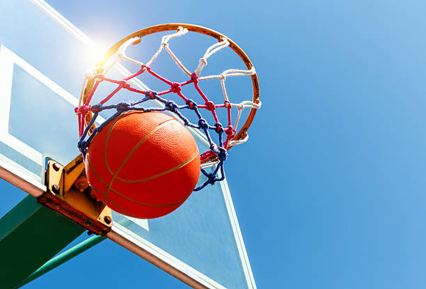 Basketball in a net against blue sky