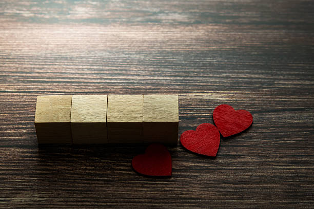 istock Three red heart shape beside cube on wooden table 2231343027