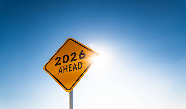 2026 AHEAD written on yellow traffic signpost against clear blue sky background