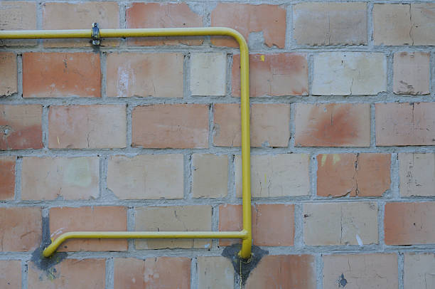 Yellow gas pipe on a brick wall. House construction concept.