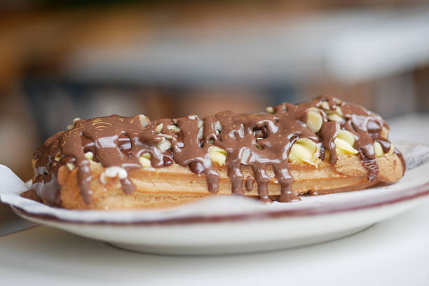 A decadent eclair with chocolate icing and sprinkled nuts awaits enjoyment.