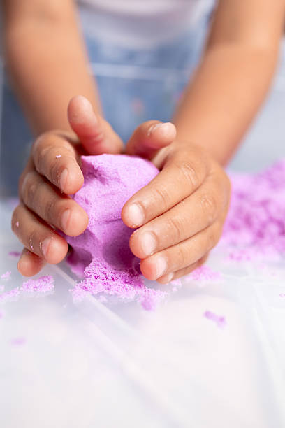 istock Child molding purple kinetic sand with hands 2231355821