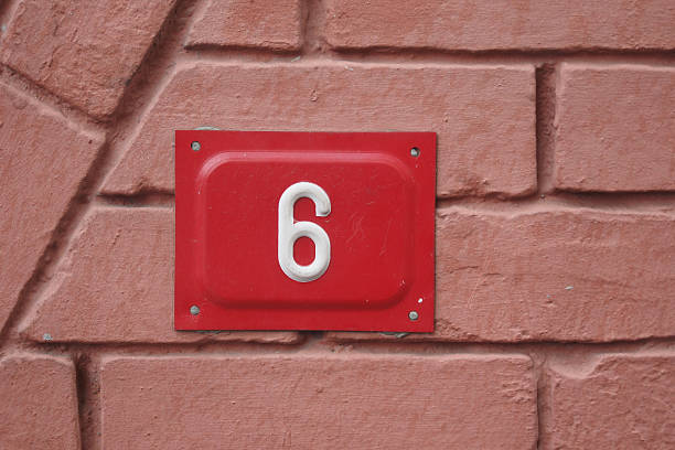 A bold red number six stands out against a pink brick background.