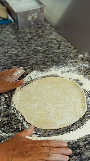 istock Pizza chef preparing pizza dough on floured granite countertop 2231356529