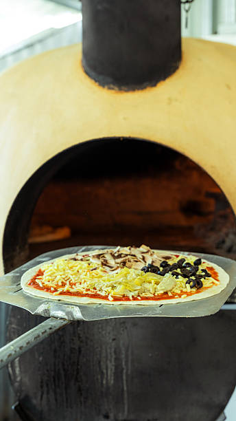 istock Pizzaiolo placing raw pizza into wood fired oven 2231357031