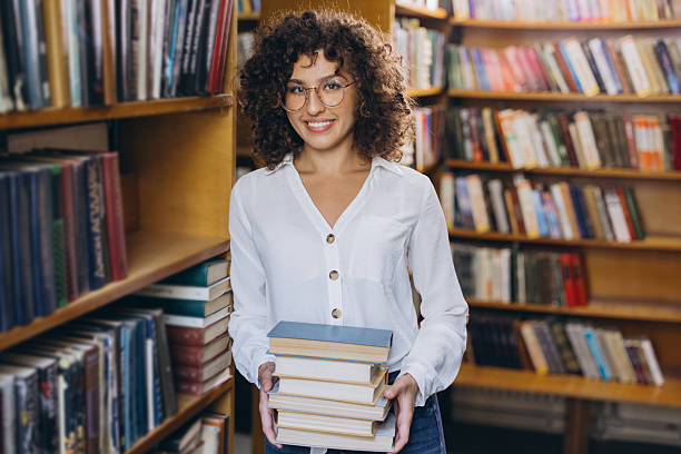 istock Smiling student holding books in the library 2231359589