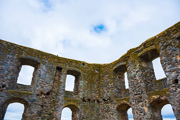 Ruined stone castle walls against cloudy sky.