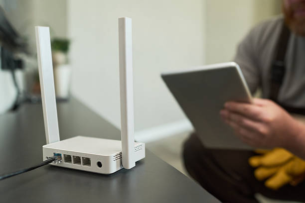istock Caucasian Middle Aged Man Configuring Wireless Router While Holding Digital Tablet 2231361492
