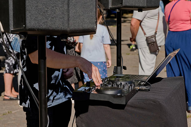 Close-up of a DJ hand adjusting sound controls on a professional mixing console at an outdoor event. Music performance and entertainment concept.