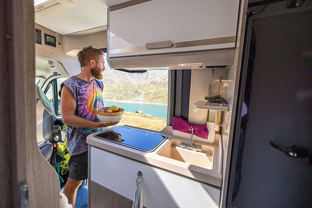 istock Man Preparing Food Inside Camper Van Kitchen By Lake 2231368421