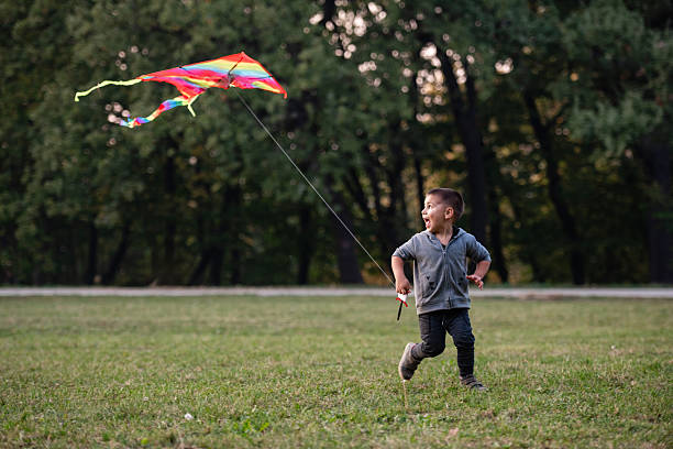 istock Happy child running with kite in park during summer day 2231370054