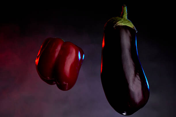This image features a glossy red chili pepper resting on a rich purple background, highlighting its tapered end and curved shape, perfect for food photography or design projects.
